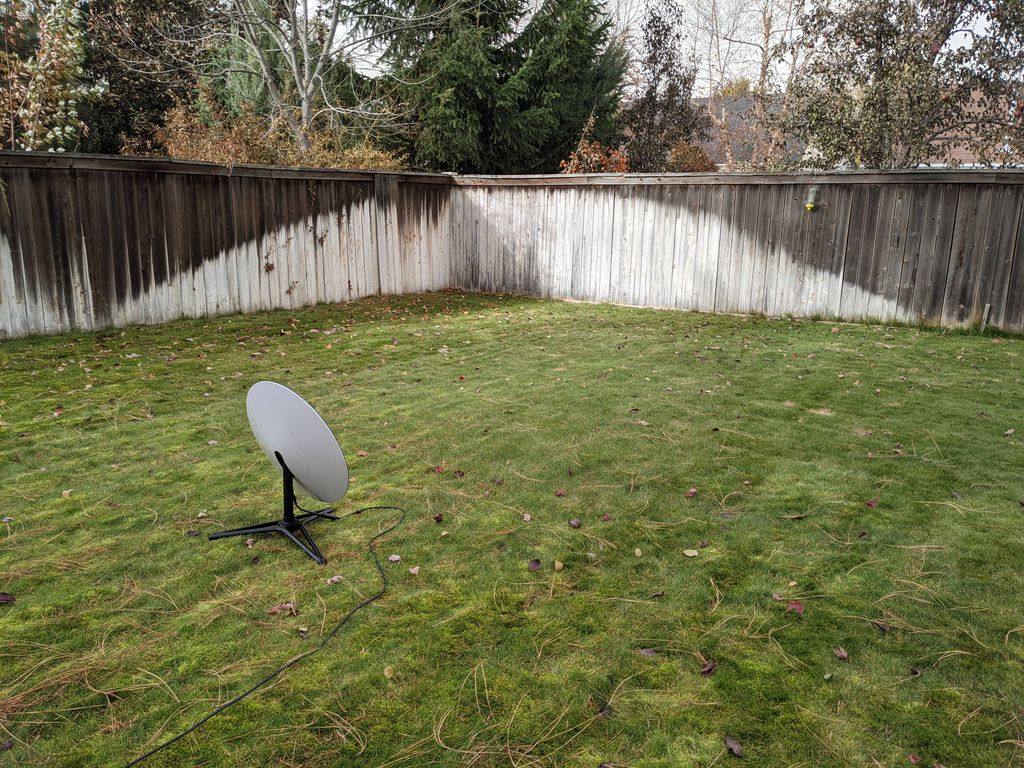 Imagem demonstrando o posicionamento de uma antena de recepção da StarLink em um gramado