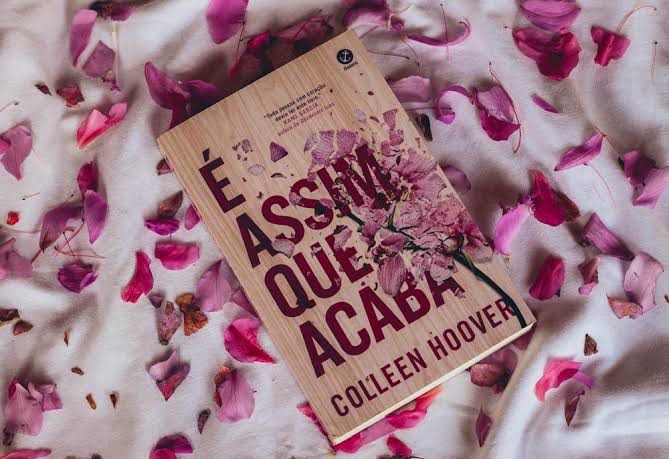 Imagem do livro "É assim que acaba", escrito por Collen Hoover, com pétalas de flor espalhadas atrás.