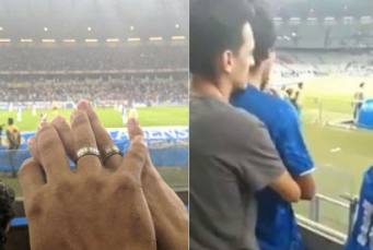 imagem os dois homens aparecem se abraçando vendo um jogo de futebol