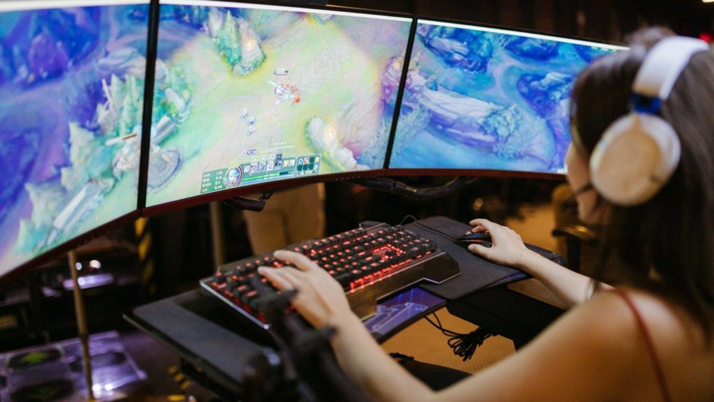 a imagem mostra um mulher frente a vários monitores jogando vídeo game