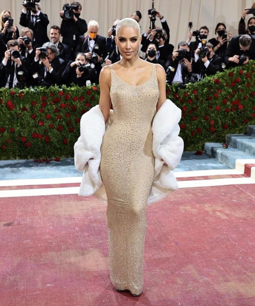 a imagem mostra Kim Kardashian ao centro usando o famoso vestido brilhoso de Marilyn Monroe