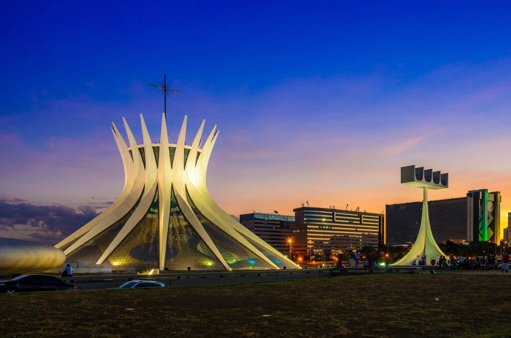 Paisagem de Brasília ao anoitecer, composta pela Catedral e outros prédios no eixo monumental.