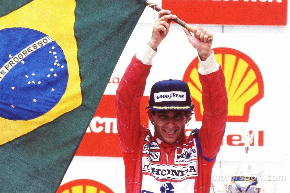 Aryton Senna comemorando a vitória enquanto levanta uma bandeira do Brasil.