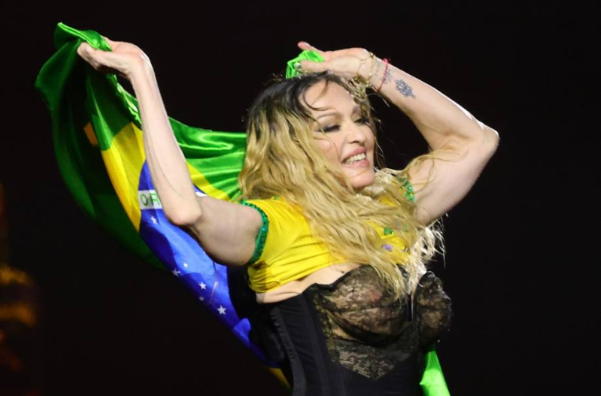 Foto da cantora Madonna segurando a bandeira do Brasil em seu show.