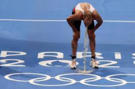 Atleta vomitando em cima da logo das Olimpíadas de Paris em 2024.